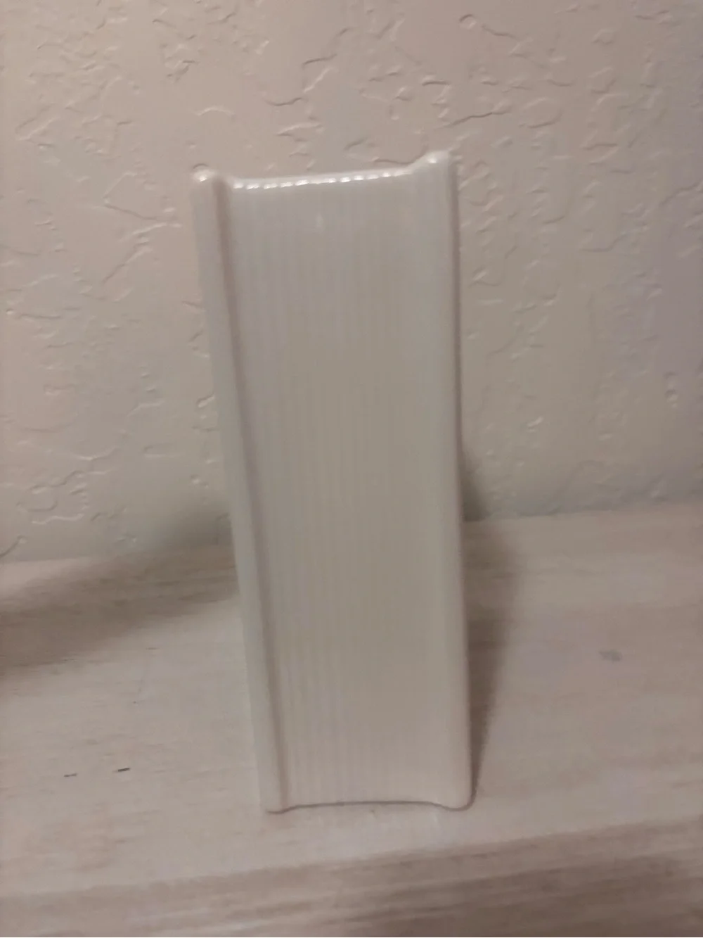ceramic book vase with green floral swirls and the words…